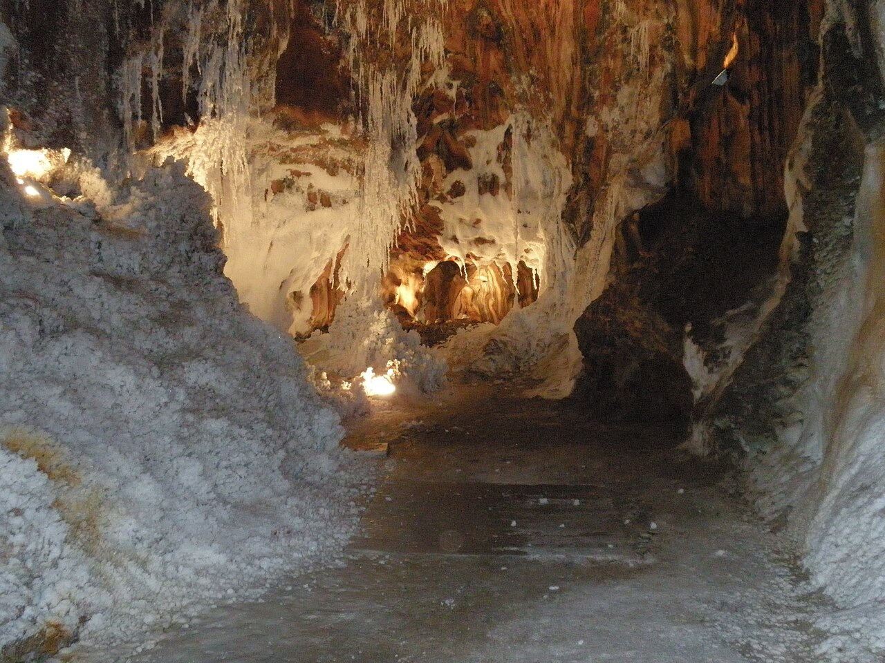 Interior de la mina de sal de Cardona en Barcelona, mostrando espectaculares formaciones de estalactitas de sal blanca y paredes de sal gema iluminadas en las galerías subterráneas.
