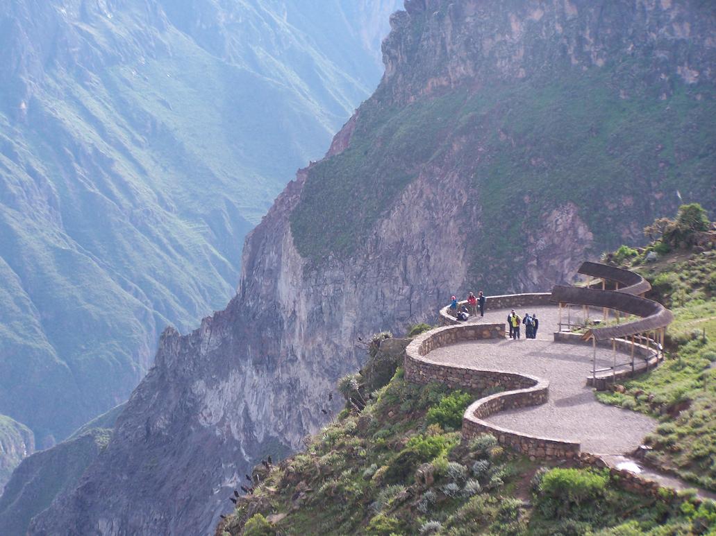 Mirador Cruz del Cóndor, Cañón del Colca Vistas panorámicas desde el mirador de Cruz del Cóndor sobre el Cañón del Colca, con turistas y una bandada de cóndores volando cerca del borde del acantilado en Arequipa, Perú